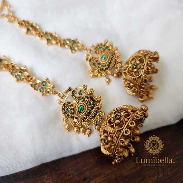 Peacock motifs are the primary design element of Jumka earrings with ear chains. The stud of these jumka earrings is a peacock motif set with emerald stones; the beauty of the earring stud is further enhanced by a string of golden pearls coupled at the base with a flower motif on a golden hoe. The jumkas